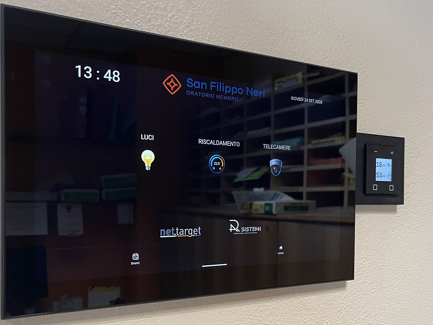 Pannello touch di supervisione KNX installato a parete, con termostato a fianco